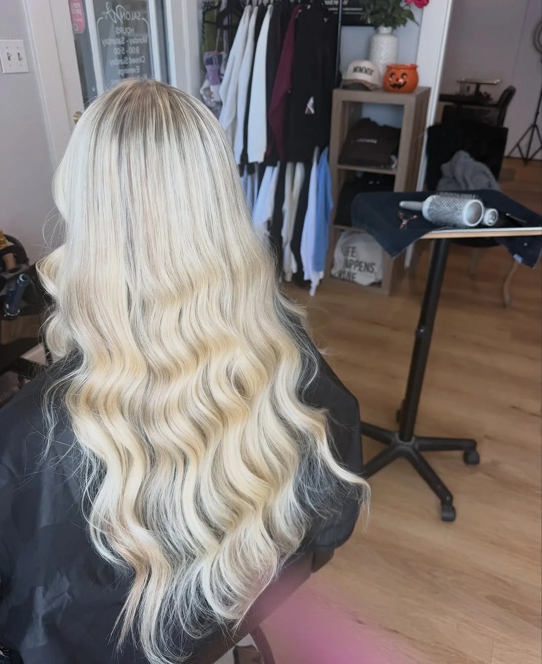 Long platinum blonde hair styled in soft waves, photographed from behind in the Salon W styling chair in Lodi