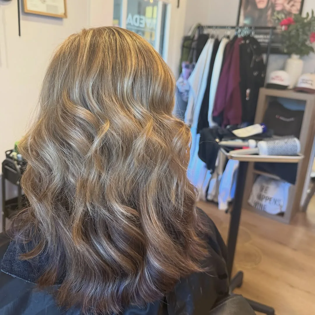 Dimensional blonde color with loose waves, photographed from behind at Salon W in Lodi